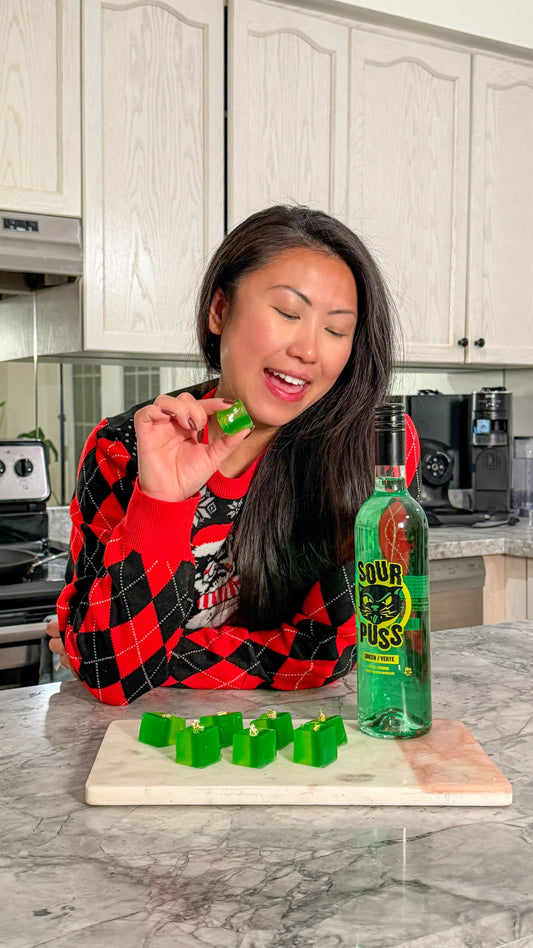 Grinch Jingle Sour Puss Apple jello cubes with gold dust beside the Sour Puss bottle