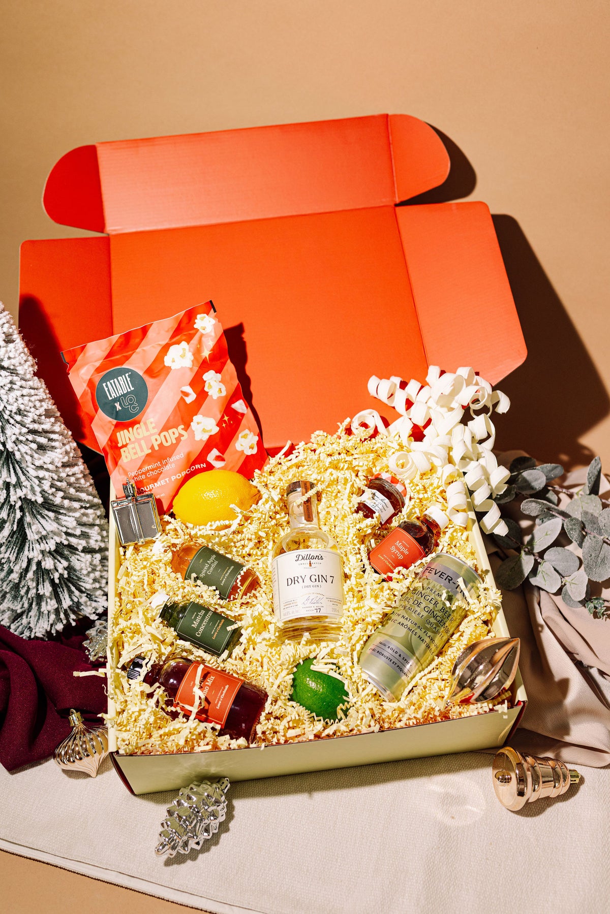 Open holiday cocktail kit gift box with mini spirit bottles, mixers and garnishes