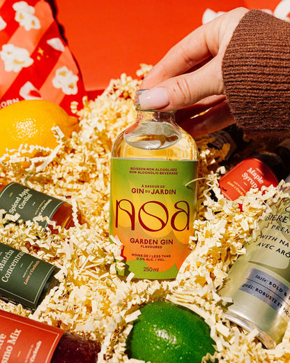 Gift basket with miniature bottles of gin and a lime, with a hand reaching in to pick up a bottle.